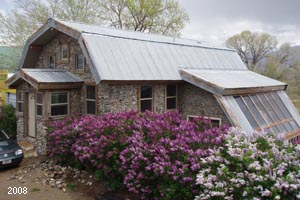 Slipform stone house with lilac bushes.